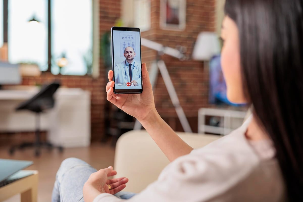 Woman having a video consultation with a doctor on her phone at home